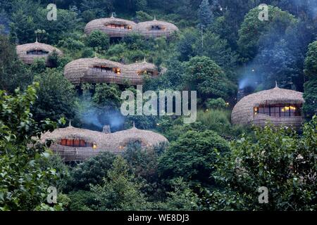 Ruanda, Parco Nazionale Vulcani, con tetto di paglia di ville di Bisote lodge del Wildreness Safaris hotel group, emergenti da una collina ricoperta di vegetazione Foto Stock