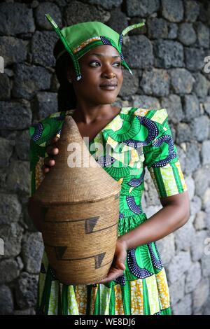 Ruanda, Parco Nazionale Vulcani, giovane donna ruandese in abito tradizionale, membro dello staff di Bisate Lodge, portante un basketry Foto Stock