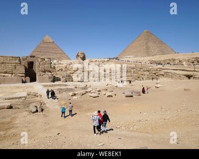 L'Egitto, al Cairo, Giza, Sito Patrimonio Mondiale dell'UNESCO, le Piramidi di Giza, gruppo di turisti di fronte alla sfinge e piramidi di Kheops, Khephren Foto Stock