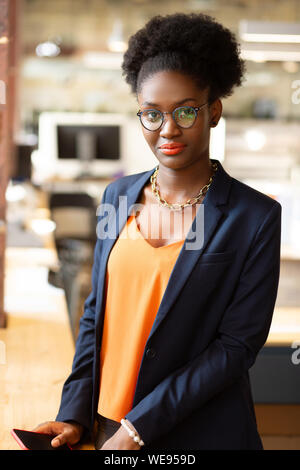 Dark-eyed curly donna con labbra luminose in piedi vicino a tabella Foto Stock