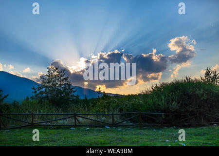 Estate tramonto scena con raggi solari luce andando verso il basso e verso l'alto attraverso le nuvole Foto Stock