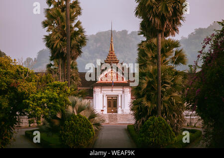 Il 4 aprile, 2019 Luang Prabang, Laos - Luang Prabang il Museo del Palazzo Reale edificio principale tra palm tree in mattinata tranquilla Foto Stock