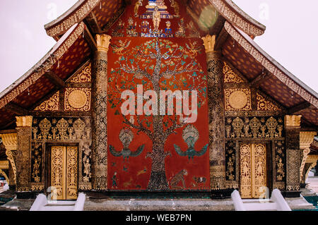 Golden Buddismo arte murale e parete mosaico "l'albero della vita" presso la sala principale di Wat Xieng Thong, Luang Prabang, Laos Foto Stock