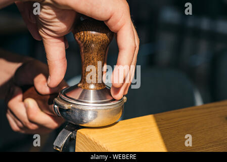 Il caffè perfetto che si adatta al vostro gusto. Barista premere il caffè con dispositivo antimanomissione in portafilter. La preparazione del caffè attrezzatura. Barista brew bere il caffè espresso in Foto Stock