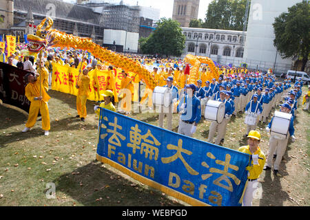 Una sfilata assembla su piazza del Parlamento a Londra, completa con un drago cinese per promuovere il Falun Dafa, un Cinese tradizionale pratica di meditazione. Foto Stock