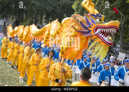 Una sfilata assembla su piazza del Parlamento a Londra, completa con un drago cinese per promuovere il Falun Dafa, un Cinese tradizionale pratica di meditazione. Foto Stock