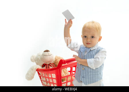 Little Boy bambino nel negozio di giocattoli con carta di credito. risparmi su acquisti. infanzia felice e cura. shopping per bambini. piccolo ragazzo andare a fare shopping con pieno Foto Stock