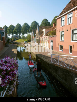 Ragazze su tavole da surf paletta nel canale della città vecchia dokkum nella provincia olandese della Frisia sul soleggiato mattina d'estate Foto Stock