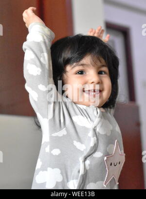 Happy Baby girl imparare a stare: pietre miliari dello sviluppo Foto Stock