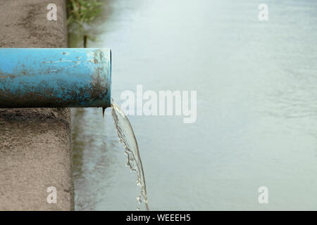 La fogna che l'acqua fluisce dall'estremità del tubo. L'acqua fluisce dal tubo. Foto Stock