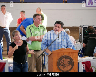 Springfield, Illinois, Stati Uniti d'America. Il 13 agosto 2019. Governatore JB Pritzker parlando al 2019 Illinois State Fair del governatore Vendita di campioni. Dipartimento di Agricoltura il regista John Sullivan in camicia verde. Foto Stock