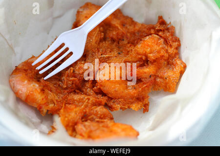 Gamberi fritti sfere con la forcella sulla parte superiore. I gamberetti sono fritte in una tazza che è coperta con la carta e ha una forcella sulla parte superiore. Foto Stock