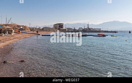 Un bacino galleggiante e le piccole barche a vela e mare sport club nei pressi della struttura navale e il porto di eilat in Israele con gli alberghi in background Foto Stock