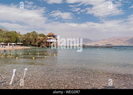 Turisti che si godono il Dolphin Reef Beach a eilat in Israele con Akaba in Giordania in background Foto Stock