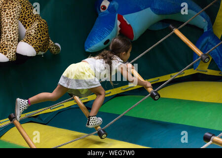 8-9 anni etnia miste ragazza asiatica sulla scaletta di corda in fiera di Santa Cruz, California Foto Stock
