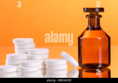 Close-up Bottiglia di medicina e pillole contro lo sfondo arancione