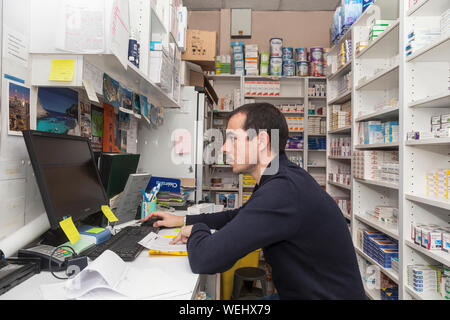 Un farmacista lavora al suo banco in una farmacia a Tours in Francia. Foto Stock