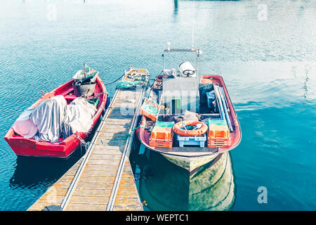 Due multicolore barche da pesca ormeggiate al molo sul mare blu Foto Stock