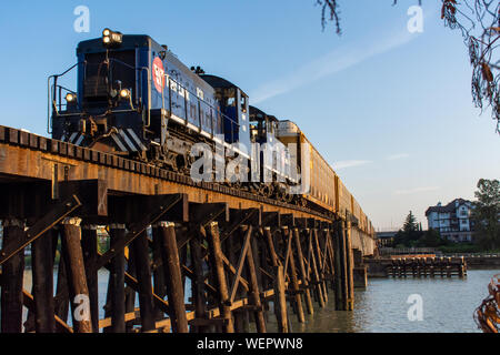 'New Westminster, British Columbia, Canada - 8/3/2019: Nuovo Molo di Westminster in legno antico ponte del treno con il sentiero canadese link la guida attraverso la sera Foto Stock