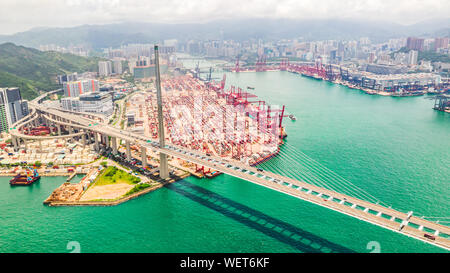 Cityscape drone vista aerea della città di Hong Kong, porta il distretto industriale, container ship, gru, auto il traffico sul ponte Stonecutters Bridge Foto Stock