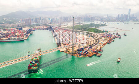 Cityscape drone vista aerea della città di Hong Kong, porta il distretto industriale, container ship, gru, auto il traffico sul ponte Stonecutters Bridge Foto Stock