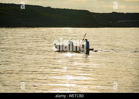 Sea kayakers sguazzare un kayak gonfiabili al tramonto al punto Penmon sull'isola di Anglesey North Wales Foto Stock