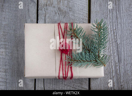 Regalo di natale Scatola sul tavolo di legno, artigianato avvolgimento, pergamena, spago, abete ramoscelli, carino semplice last minute presente fatti a mano. Vista dall'alto. Foto Stock