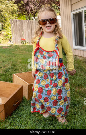 2 anno vecchia ragazza divertirsi la modellazione di nonna occhiali da sole e al di fuori della catenaria Foto Stock