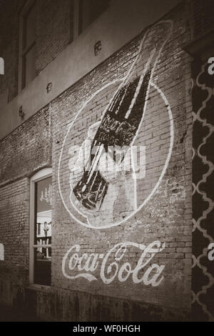 Un vecchio annuncio vintage per la Coca Cola di fading su un vecchio muro di mattoni di un edificio in downtwown Tupelo, Mississippi, Stati Uniti d'America, in seppia Foto Stock