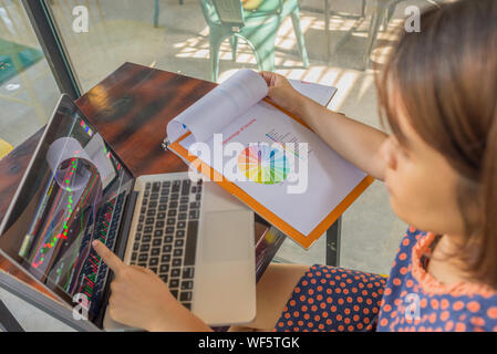 Donna asiatica guardando candelabro finanziario grafico su schermo di computer portatile Foto Stock