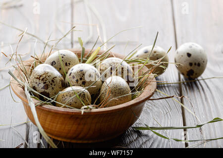 Organico fresco uova di quaglia in ciotola di legno rustico tavolo da cucina. Spazio per il testo Foto Stock