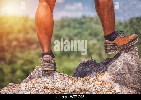 Uomo asiatico in piedi sul bordo di una scogliera alta sopra le montagne Foto Stock