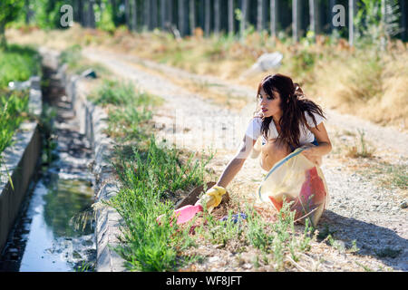 Donna lato raccogliere rifiuti dell'erba in campagna Foto Stock