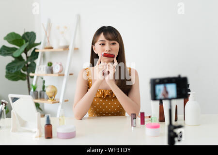 Che cosa è questo. Piuttosto giovane donna seduta nella parte anteriore della fotocamera durante la sperimentazione dei cosmetici Foto Stock