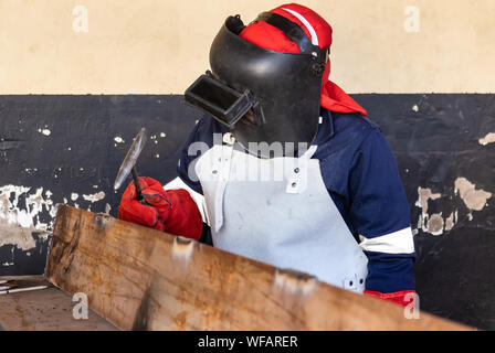 Donna lavoratrice di saldatura in un'officina del Botswana, che salda due pezzi di metallo Foto Stock