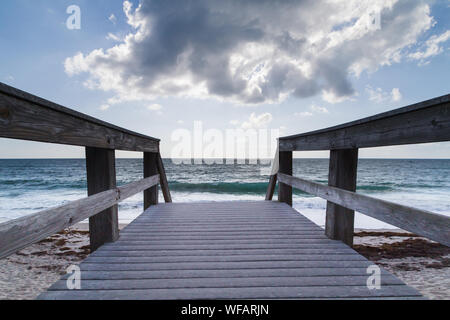 Ponte di legno che conduce alla spiaggia di fronte con una grande nuvola overhead copre il sole di mattina brevemente in Vero Beach, Florida, Stati Uniti d'America. Foto Stock