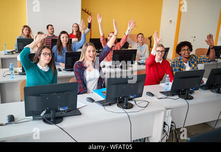 Allievi felici alzando la mano in classe su campus universitario Foto Stock