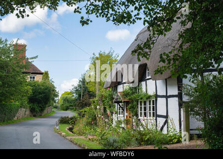 Con il tetto di paglia in bianco e nero con cornice in legno cottage e giardino. Il castello di Elmley, Cotswolds, Wychavon district, Worcestershire, Inghilterra Foto Stock