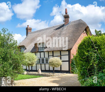 Con il tetto di paglia in bianco e nero con cornice in legno cottage e giardino. Bredons norton, Cotswolds, Wychavon district, Worcestershire, Regno Unito Foto Stock