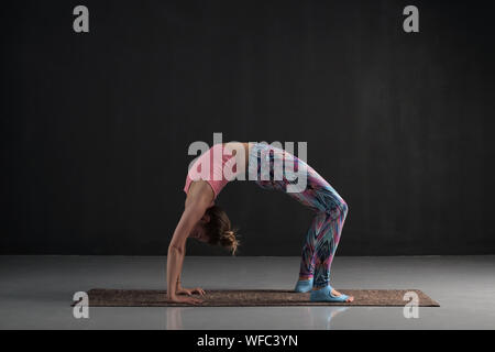 Sporty giovane donna le pratiche yoga asana chakrasana o urdva dhanurasana o ruota pongono. Studio a piena lunghezza shot Foto Stock