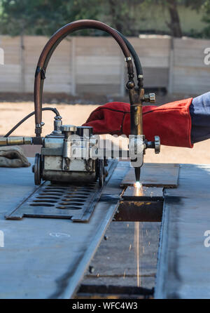 Saldatore Motswana lavoratore in un workshop del Botswana, utilizzando una torcia di acetilene per tagliare in linea retta, rullo torcia, Foto Stock