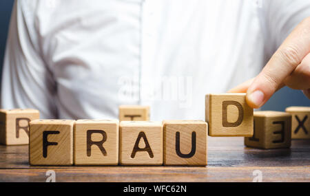 Blocchi di legno con la parola la frode e l'uomo. Barare bianco-collare . La criminalità. Il furto di un altro albergo. Anti-corruzione nel settore finanziario. De Foto Stock