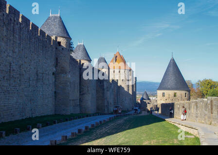 I turisti escursioni tra i bastioni di Carcassonne storica fortezza in pietra sulla giornata soleggiata con cielo blu. Francia, Europa Foto Stock