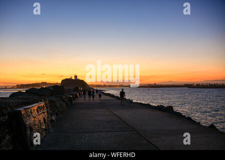 Testa Nobbys rompe il muro con il faro e il porto di entrata con tramonto Newcastle New South Wales NSW, Australia Foto Stock