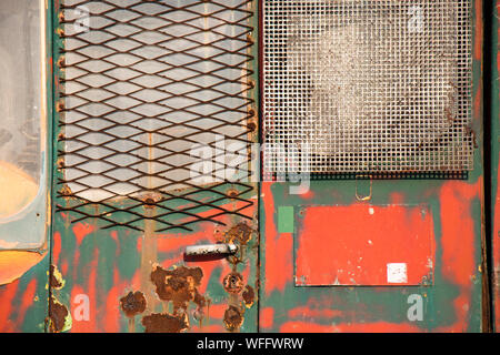 Weathered vibrante layered verde e rosso vernice incrinata sul metallo arrugginito porta, un dettaglio di una vecchia costruzione vintage sfondo del veicolo Foto Stock