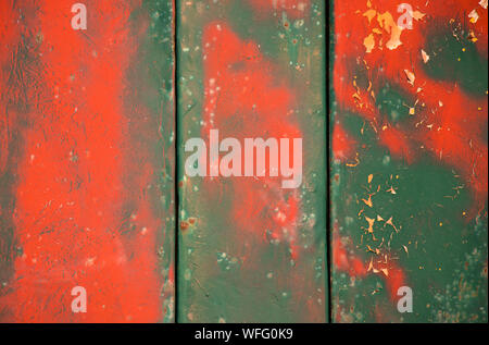 Weathered vibrante layered verde e rosso vernice incrinata sul metallo, un dettaglio di un vecchio vintage sfondo del veicolo Foto Stock