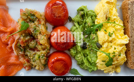 Salmone affumicato, uova strapazzate, avocado, pomodori, interi di frumento toast, melanzana Foto Stock