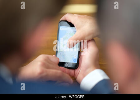 Due imprenditori in ufficio al banco informazioni studio sullo schermo dello smartphone Foto Stock