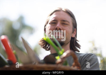 Ritratto di un uomo che porta un cesto pieno di attrezzature da giardinaggio, Germania Foto Stock