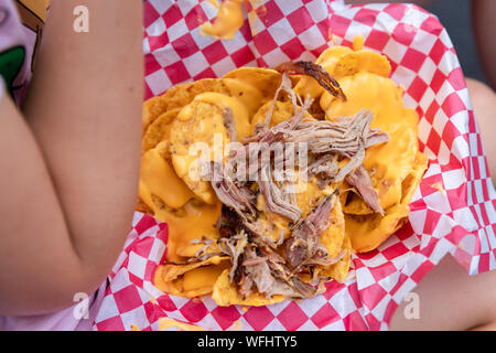 La carne di maiale nachos con formaggio di ragazze in giro, ad una fiera Foto Stock